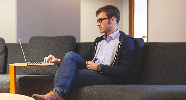a person sitting on a sofa and working on a laptop