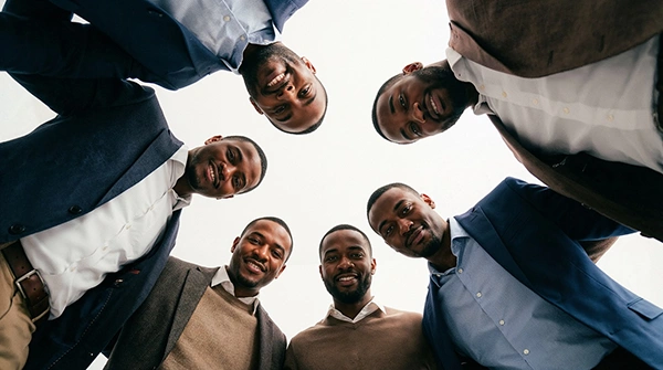 six men standing in a group by holding hands with each other in smiling faces